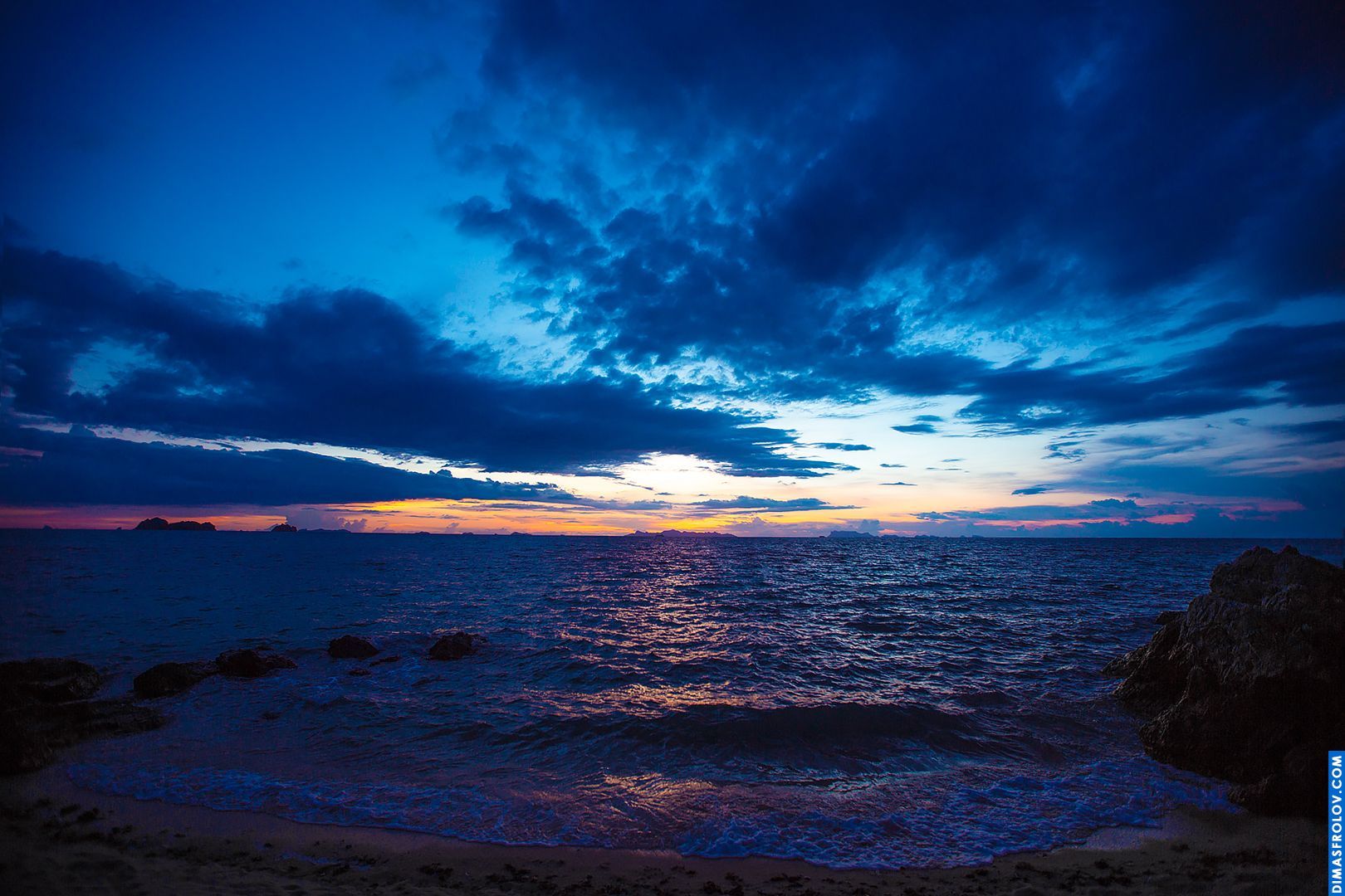 Moody coastal scene with dark clouds over the ocean, capturing the light reflecting on the water
