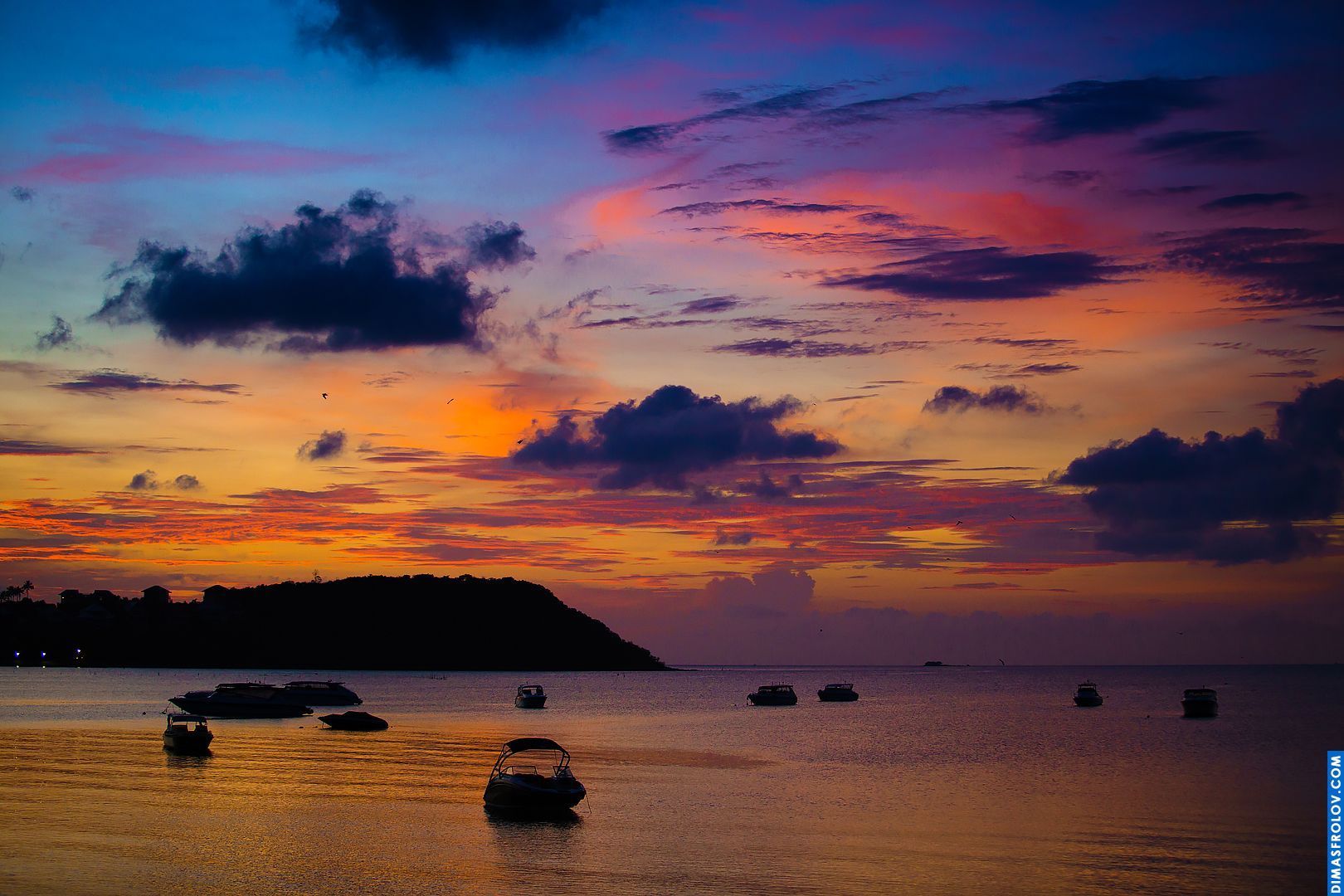 Vibrant sunset over the ocean with colorful clouds and a calm, reflective surface of the water